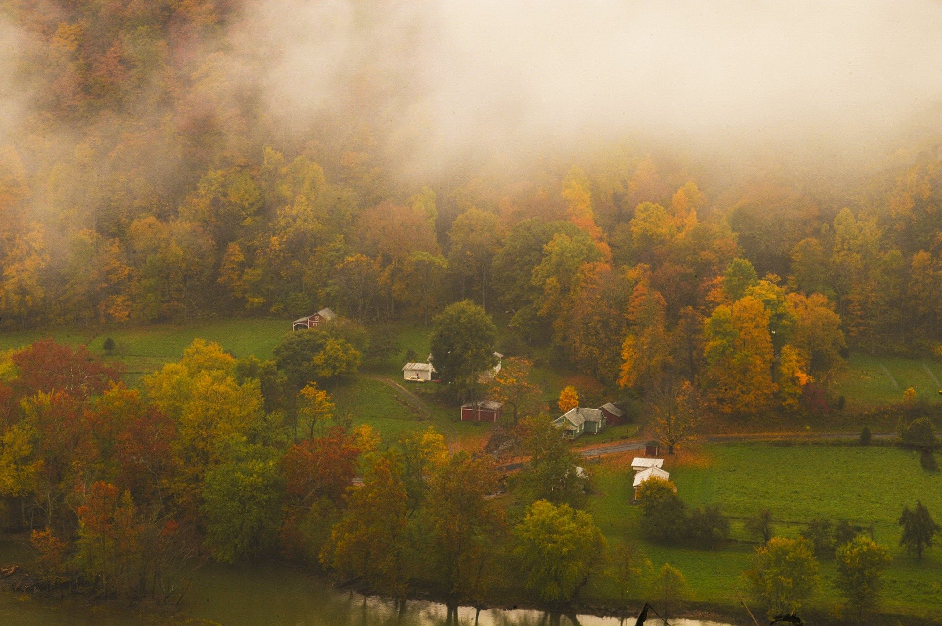 Mist lifting off a West Virginia valley of small farms surrounded by hardwood forest in full autumn colour