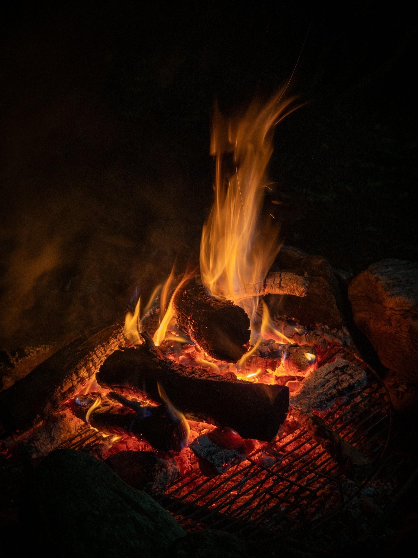 Logs burning down to coals in a campfire ring after dark
