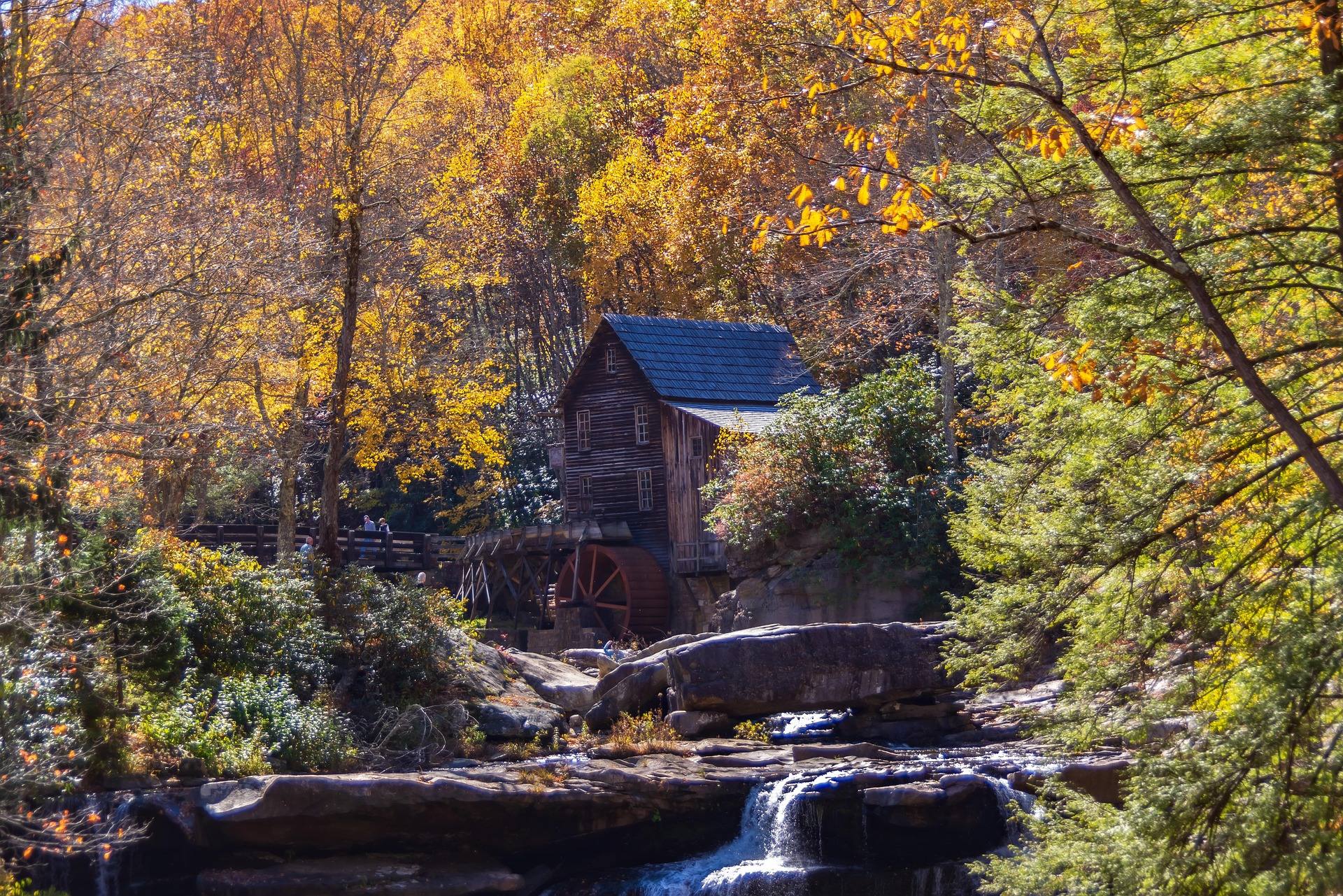 Glade Creek Grist Mill at Babcock State Park, West Virginia, framed by peak fall foliage above a rocky creek