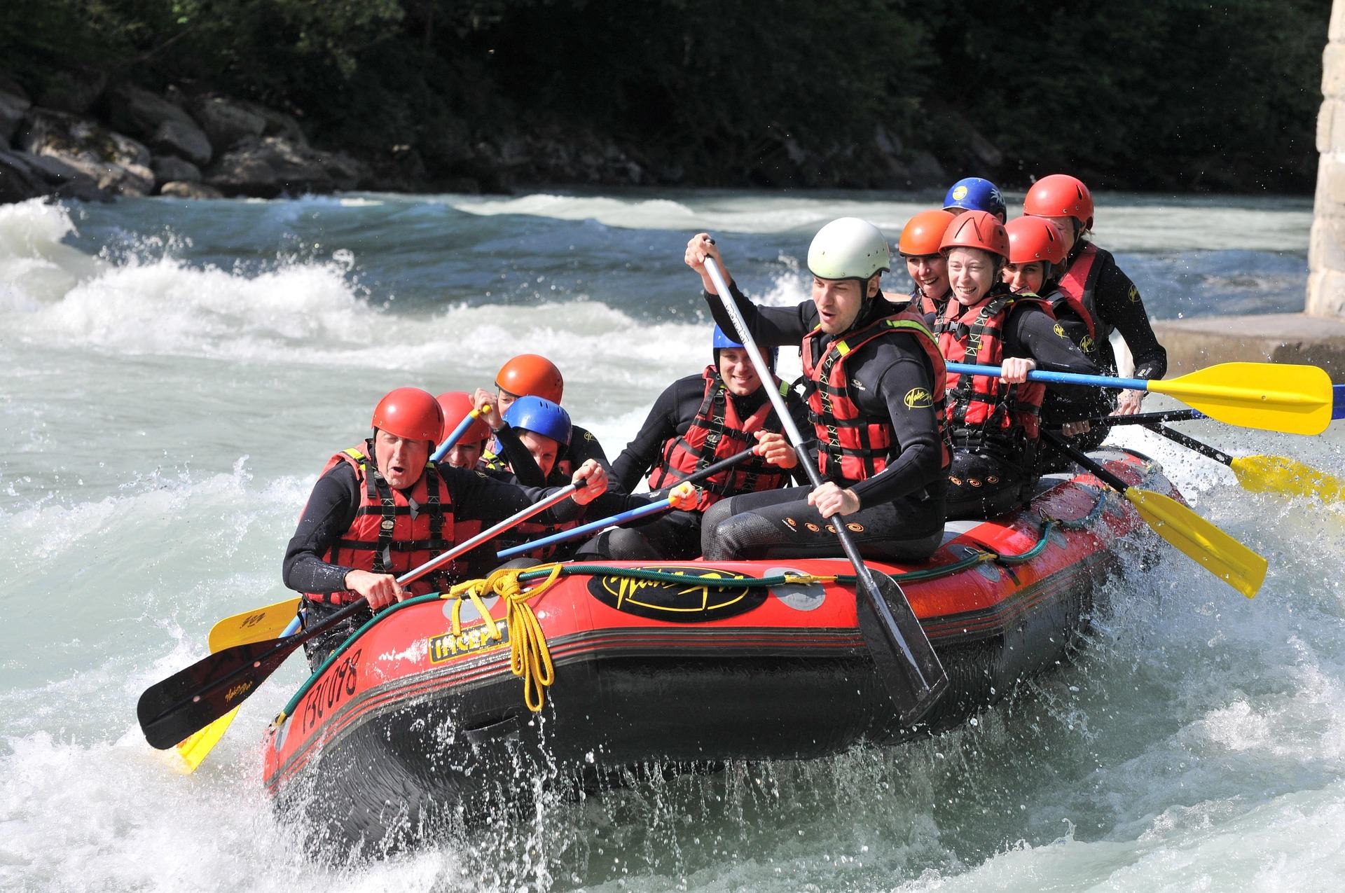Group of rafters in helmets and life jackets paddling a guided whitewater rafting trip through big rapids