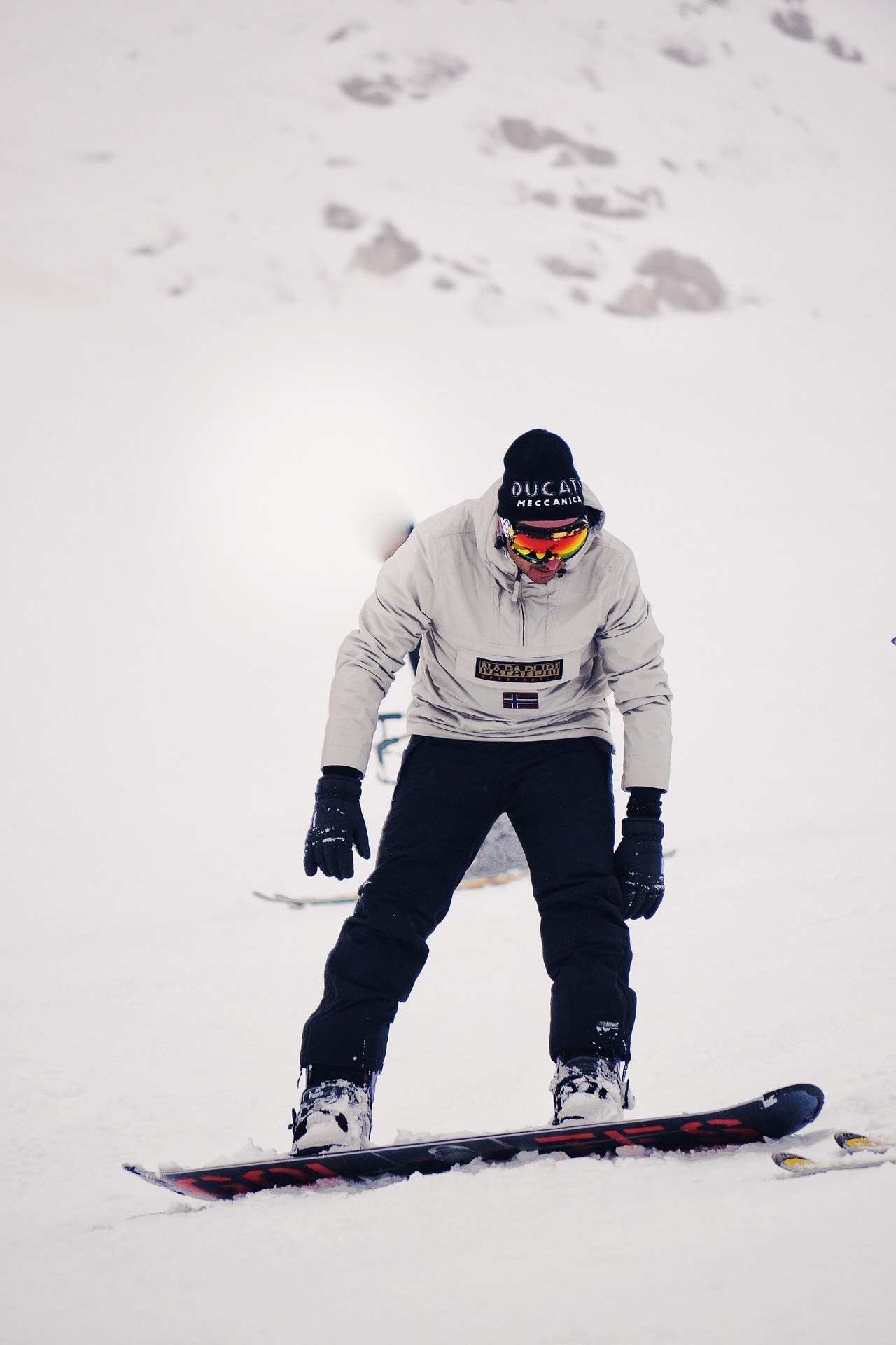 Snowboarder riding down a snow-covered slope on a winter day at a mountain ski resort