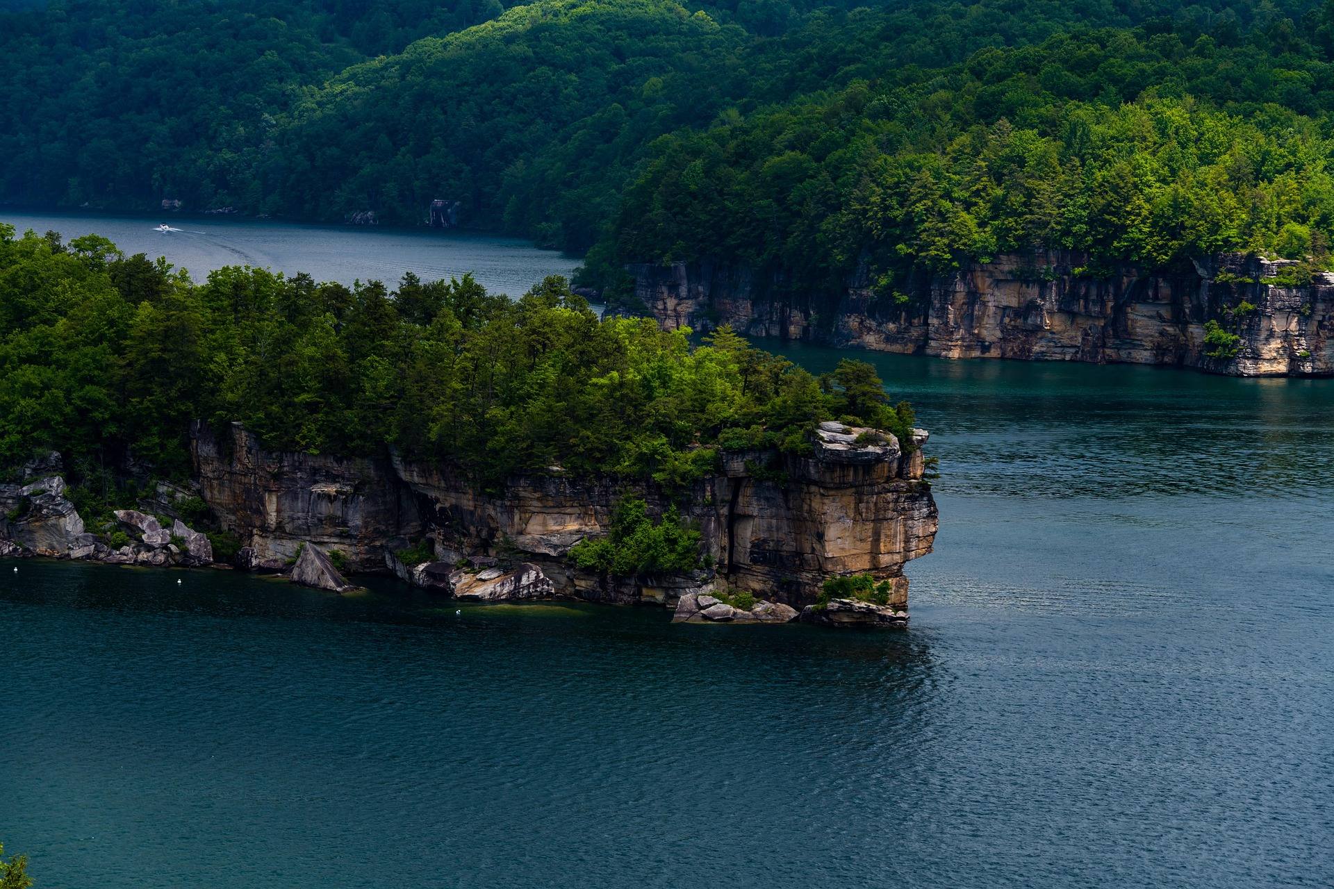 Sandstone cliffs and a wooded point jutting into the clear blue-green water of Summersville Lake, West Virginia