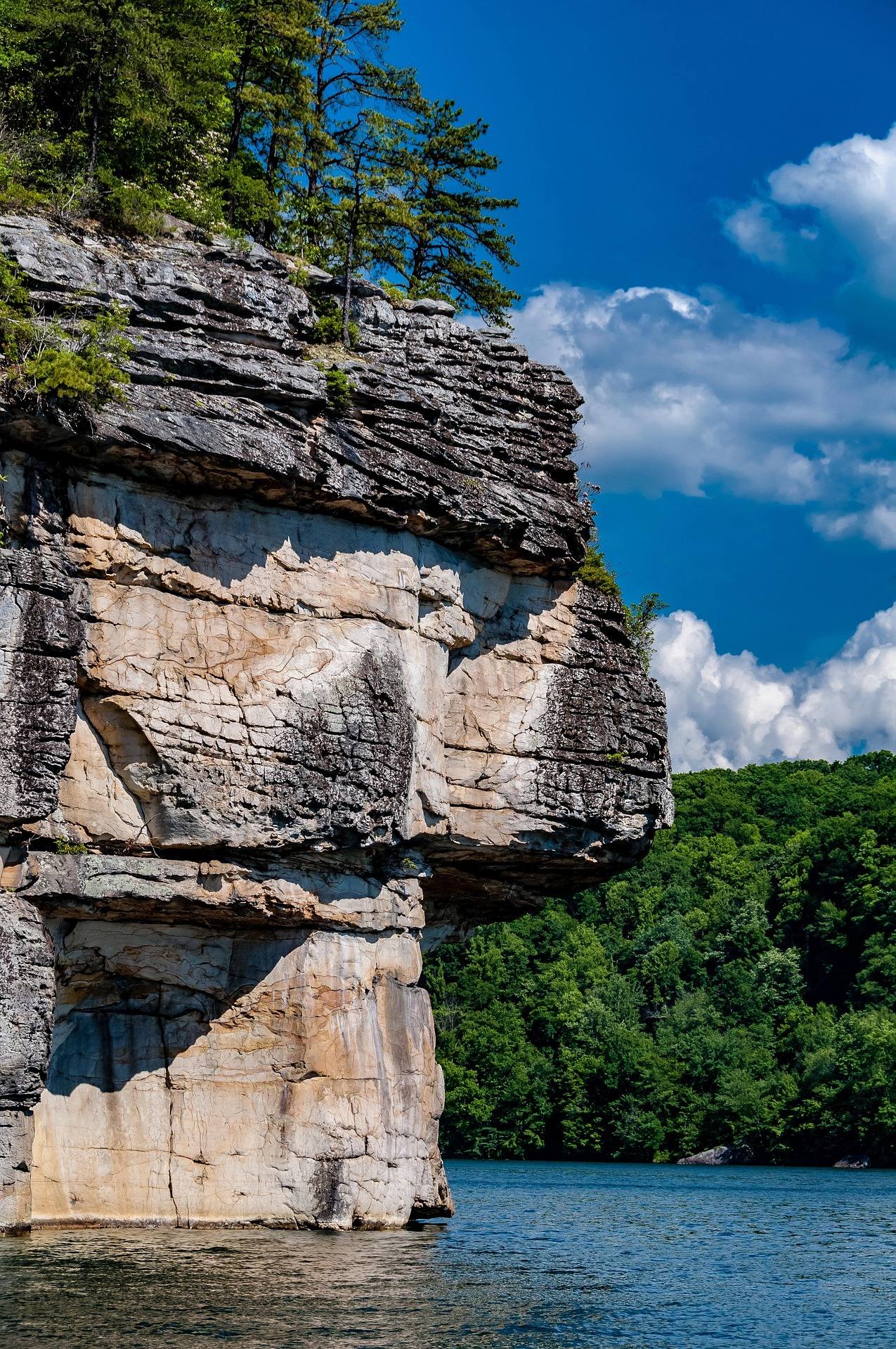 Towering sandstone cliff face rising straight out of Summersville Lake, a deep water soloing climbing spot in West Virginia