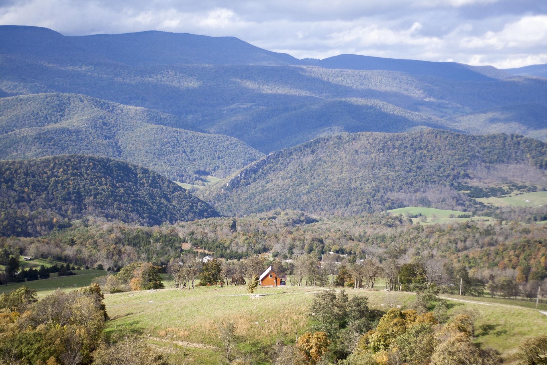 A broad West Virginia highland valley of farms and pasture below layered blue mountain ridges